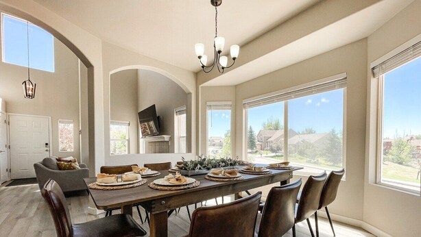 A spacious dining area with a long table, multiple chairs, and a chandelier.