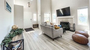 A spacious living room with a fireplace, a large flat-screen TV, and a comfortable sofa.