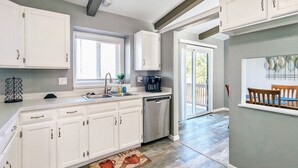 Una cocina moderna con armarios blancos, lavavajillas y cafetera.