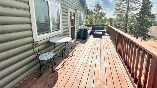 Una terraza de madera con una mesa y sillas, un sofá y una barandilla.