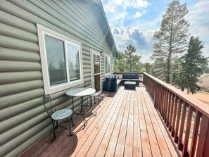 A wooden deck with a table and chairs, a sofa, and a railing.