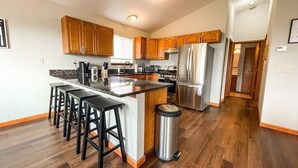 Una cocina moderna con armarios de madera, un refrigerador de acero inoxidable y una isla central con taburetes de bar.