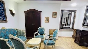A room with a wooden floor, a sofa set, a table, a cabinet, and a mirror on the wall. - Dar Diaf - El Djelfa (Djelfa)