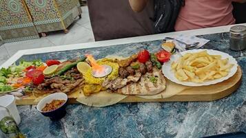 A table with a variety of dishes including grilled meats, fries, and salads.