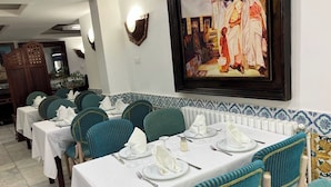 A dining area with tables set for service, chairs, and a large framed painting on the wall. - Dar Diaf - El Djelfa (Djelfa)