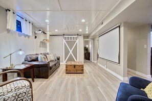 A living room with a leather sofa, a wooden chest, and a projector mounted on the wall.