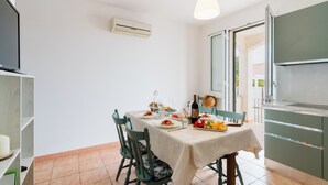 A dining area with a table set for two, a kitchen with a modern design, and a large window providing natural light. - La Dolce Vita By Just Houses SRl (Torre Pali)