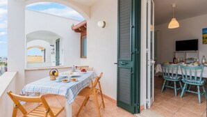 A balcony with a table set for two, a green door, and a view of the street. - La Dolce Vita By Just Houses SRl (Torre Pali)