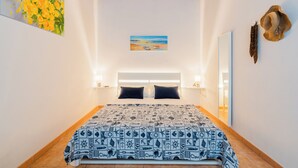 A bedroom with a large bed, a painting of flowers, a beach scene, and a hat on the wall. - La Dolce Vita By Just Houses SRl (Torre Pali)
