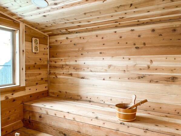 A wooden sauna room with a bench and a wooden bucket.