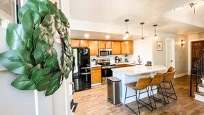 Une cuisine moderne avec des meubles en bois, des appareils en acier inoxydable et un îlot central doté de tabourets de bar.