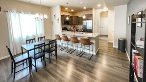 Una cucina moderna con isola centrale, pavimento in legno e illuminazione a sospensione.