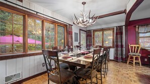 Un comedor con una gran mesa de madera, varias sillas y una araña.