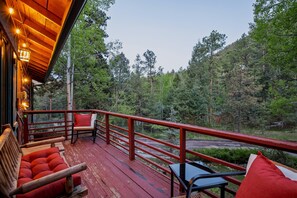 Eine Holzterrasse mit roter Brüstung, einer Holzbank, einem Tisch und einem Stuhl.