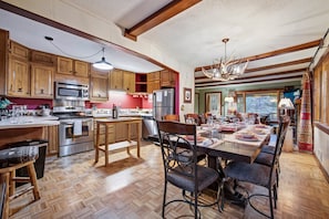 A kitchen with wooden cabinets, a dining area with a table set for four, and a large chandelier.