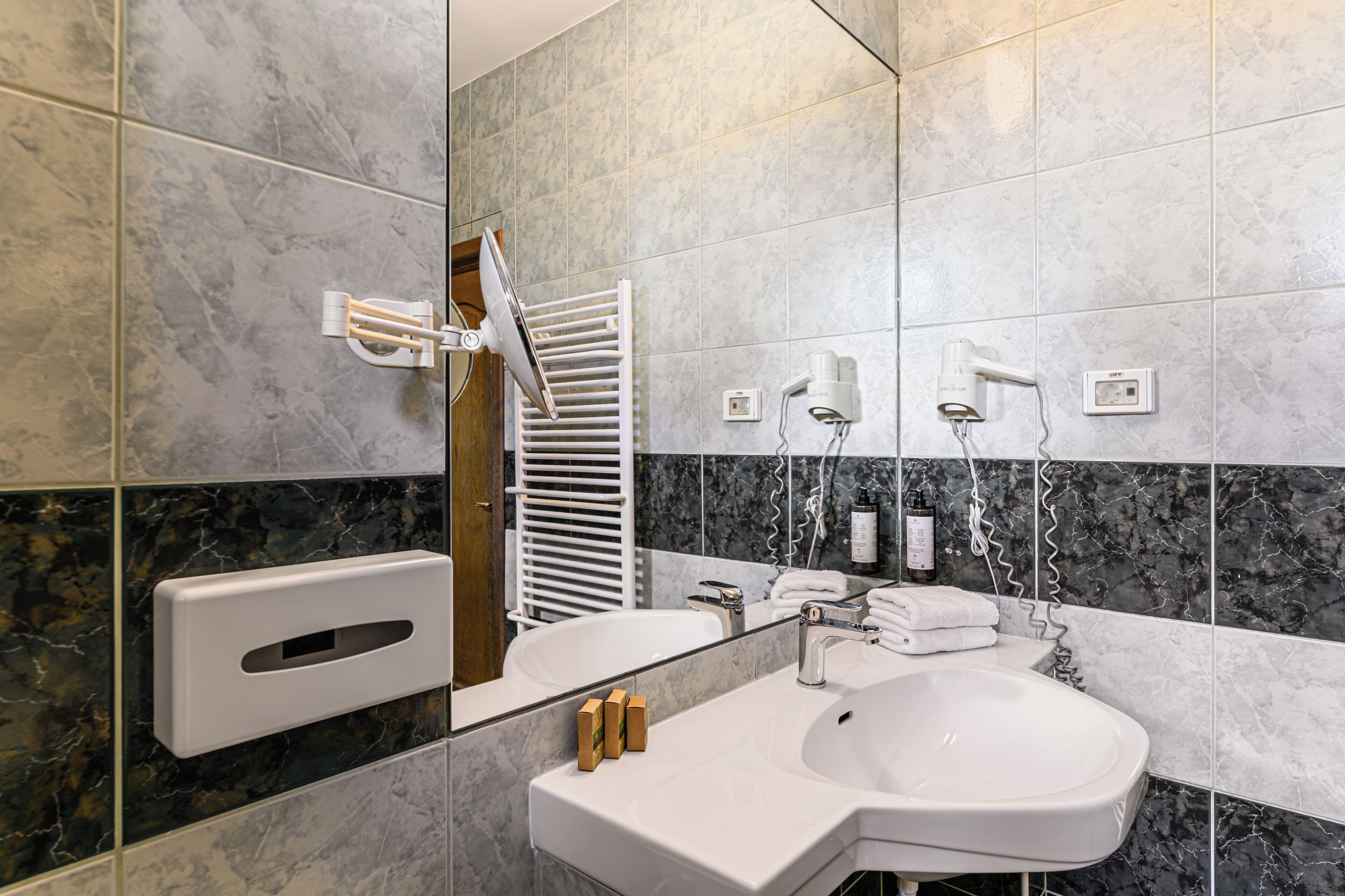 A modern bathroom with a white sink, mirror, and towel rack.