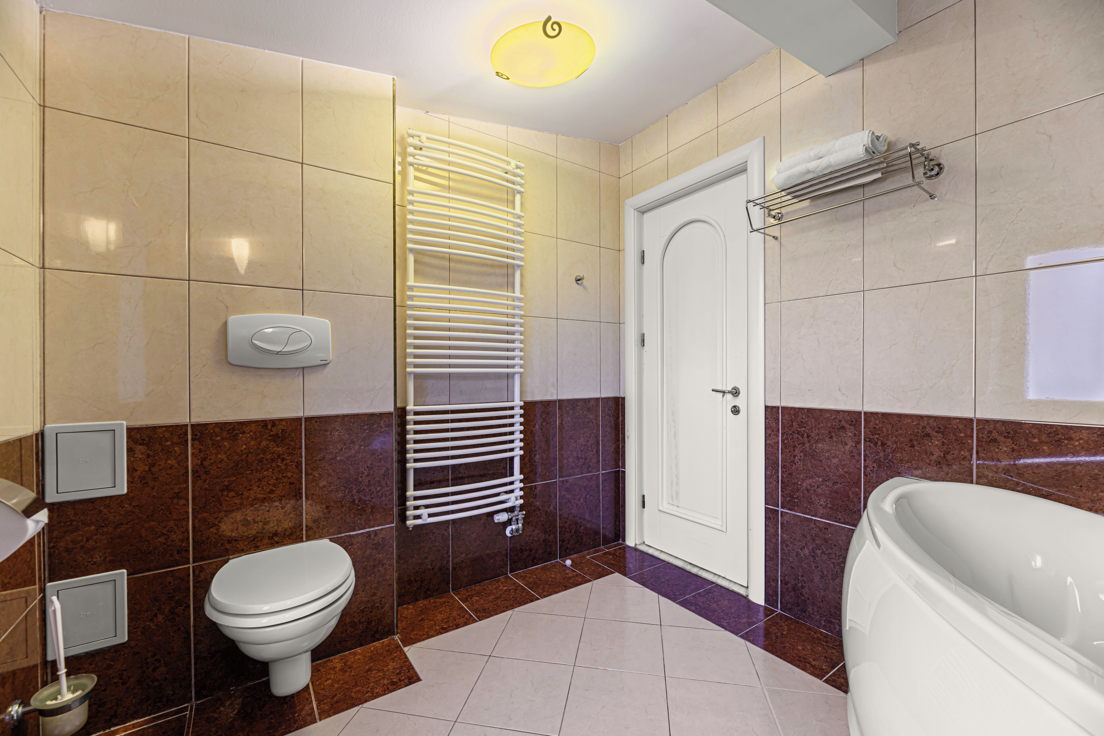 Et moderne badeværelse med toilet, håndklædestang, bruser og badekar.