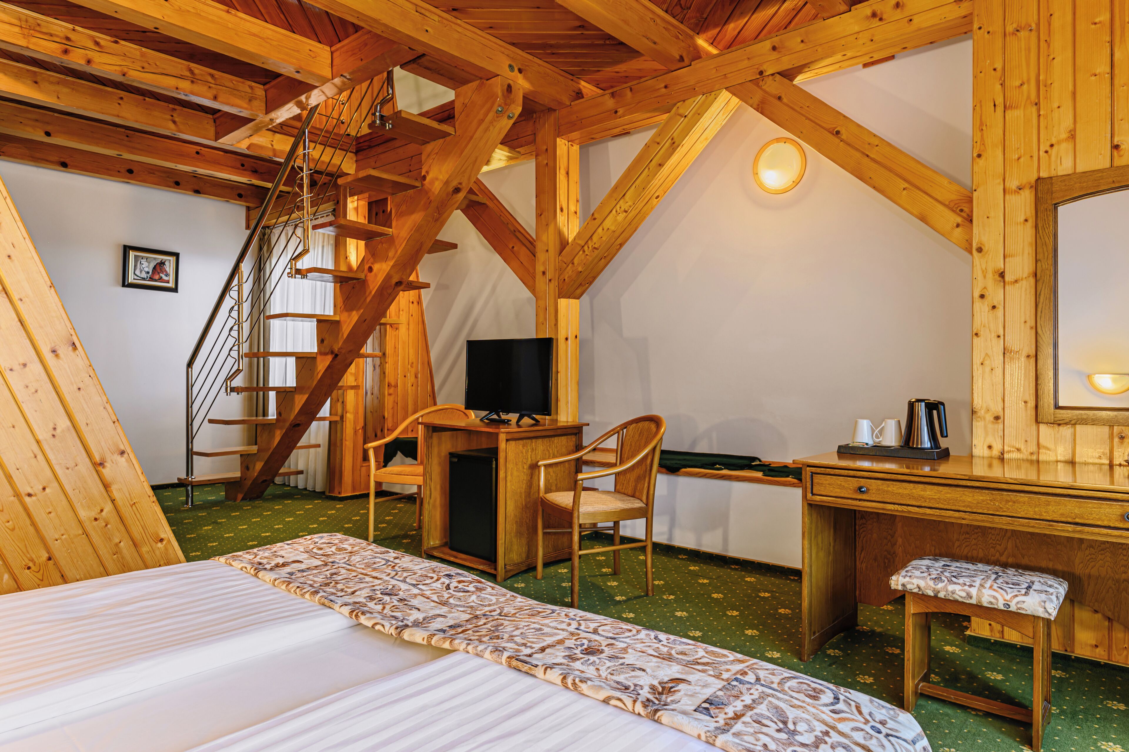 A room with a bed, a desk, a chair, a television, and a staircase.