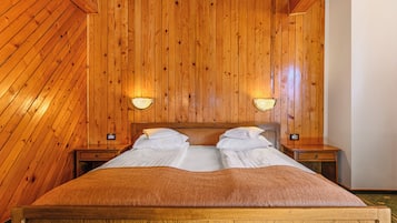 Een kamer met houten lambrisering, een bed, twee nachtkastjes en wandlampen.