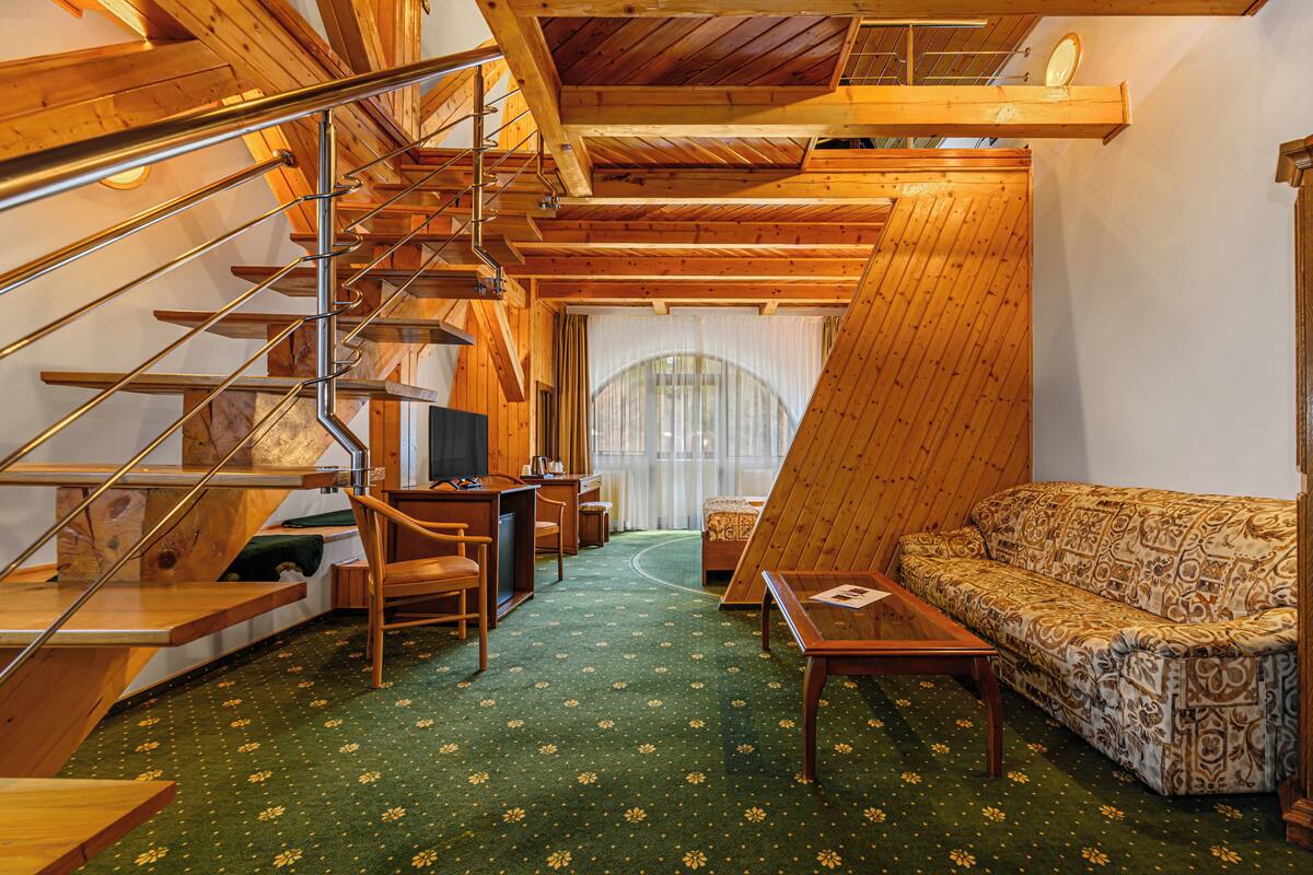 Ein Holzinnenraum mit Treppe, einer Couch, einem Couchtisch und einem Schreibtisch.