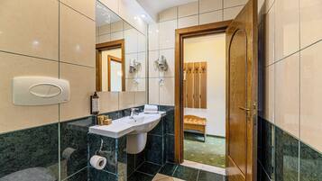 A modern bathroom with a marble sink, a toilet, and a shower area.