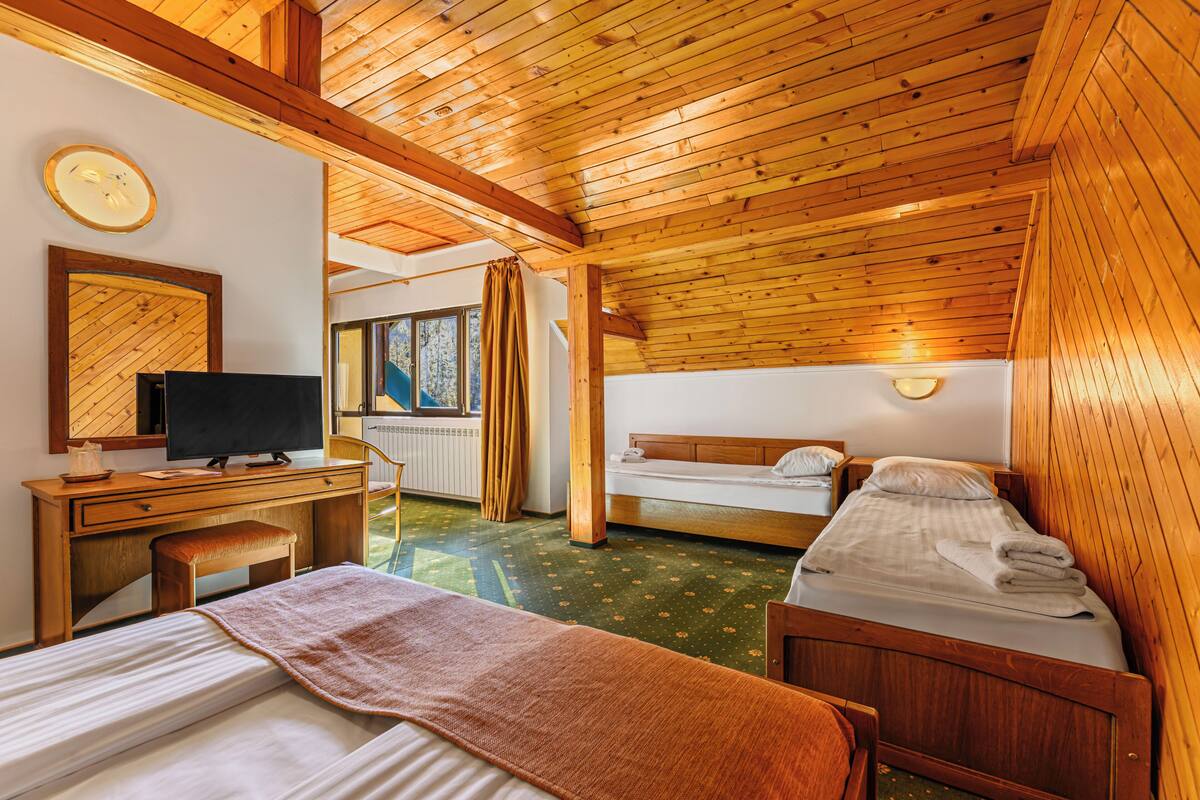Ein Zimmer in einer Holzhütte mit einem Bett, einem Schreibtisch und einem Fernseher.