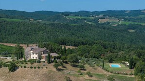 Une grande maison en pierre, avec un toit recouvert de tuiles, entourée d’un jardin bien entretenu et d’une piscine.