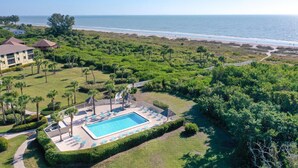 Un resort con piscina, sillas de descanso y vistas a la playa.