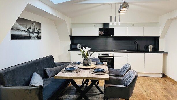 A modern kitchen with white cabinets, a black countertop, and a skylight above the dining area. - Modern vacation apartment in Anklam - right next to the city center (Anklam)