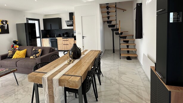Ein moderner Wohnraum mit Küche, Essbereich und Treppe.