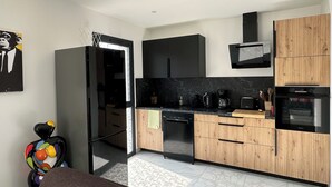 Eine moderne Küche mit schwarzen und Holzschränken, einem eingebauten Ofen und einer Kaffeemaschine.