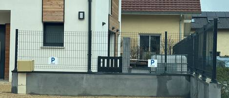 Ein Gebäude mit heller Fassade, rotem Ziegeldach und einem Schotterweg.