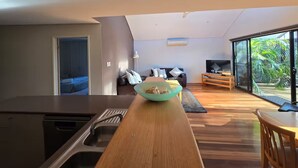 A modern kitchen with a wooden countertop, a bowl of food, and a dining area with a table and chairs.