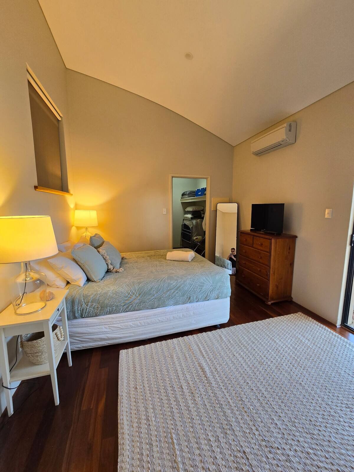 Un dormitorio con cama, mesita de noche, lámpara, cómoda y televisor.