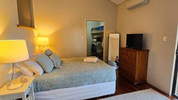 Un dormitorio con cama, mesita de noche, lámpara, cómoda y televisor.