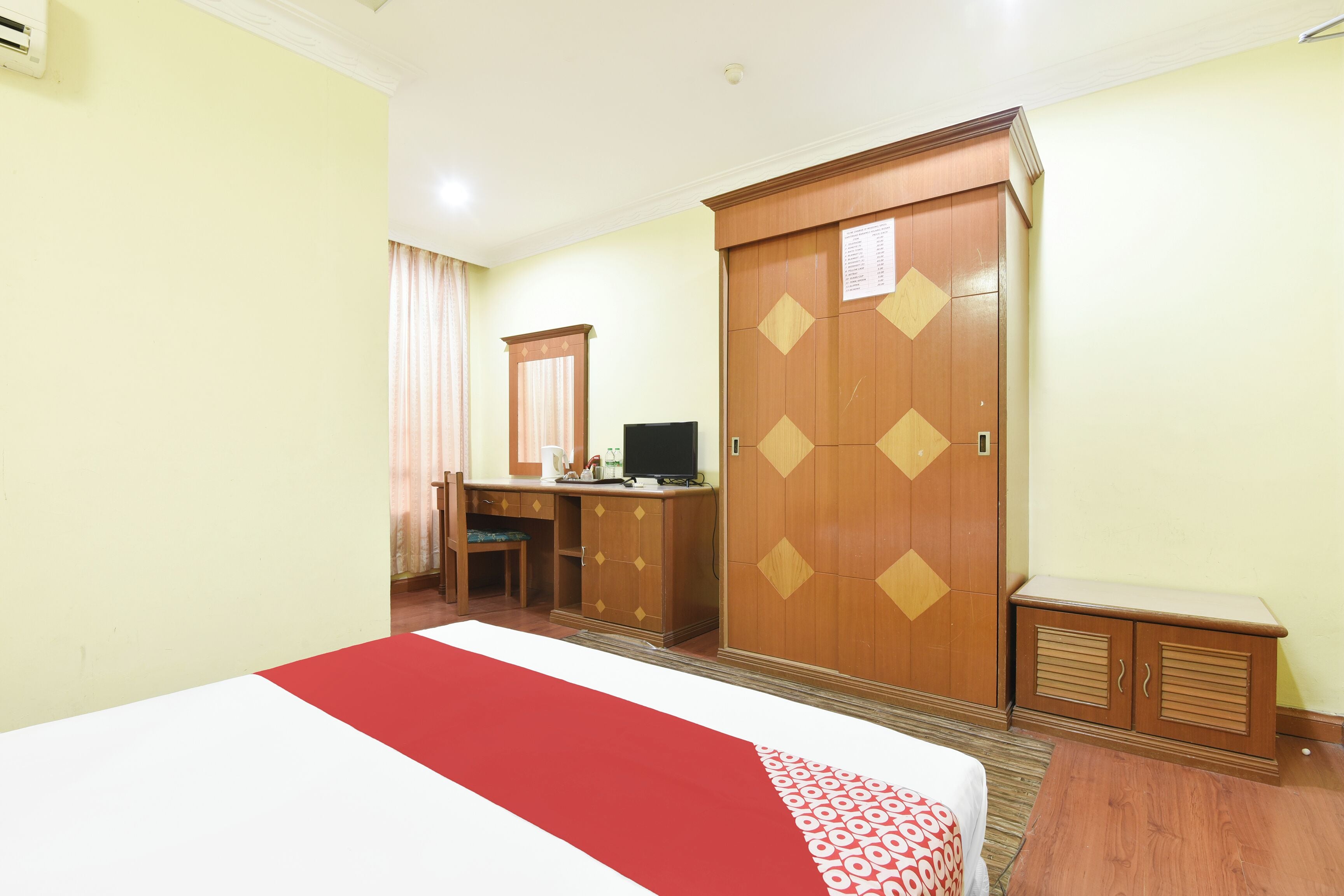 Una habitación de hotel con una cama, un escritorio, un televisor, un armario y una mesita.
