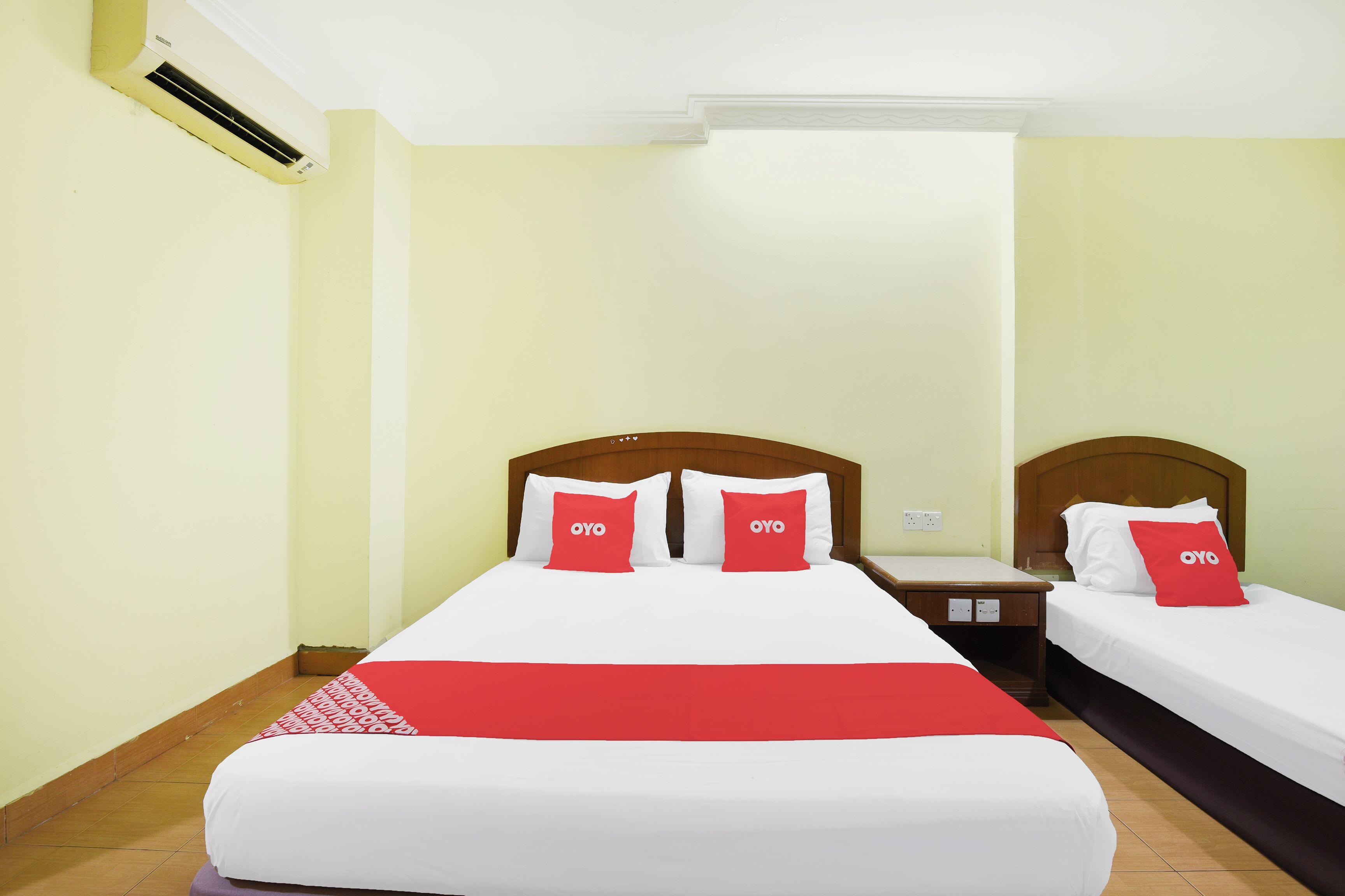 A hotel room with two beds, each with white bedding and red pillows.