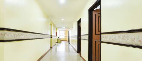 A long, narrow hallway with cream-colored walls and a tiled floor.