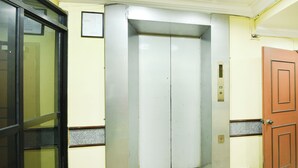 An elevator with a metallic finish, a door, and a control panel.