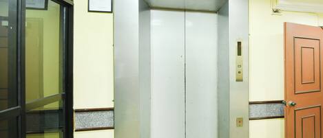 An elevator with a metallic finish, a door, and a control panel.