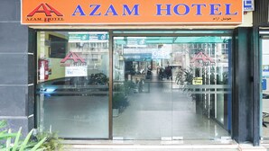 The exterior of Azam Hotel with a clear entrance, glass doors, and a visible signboard.