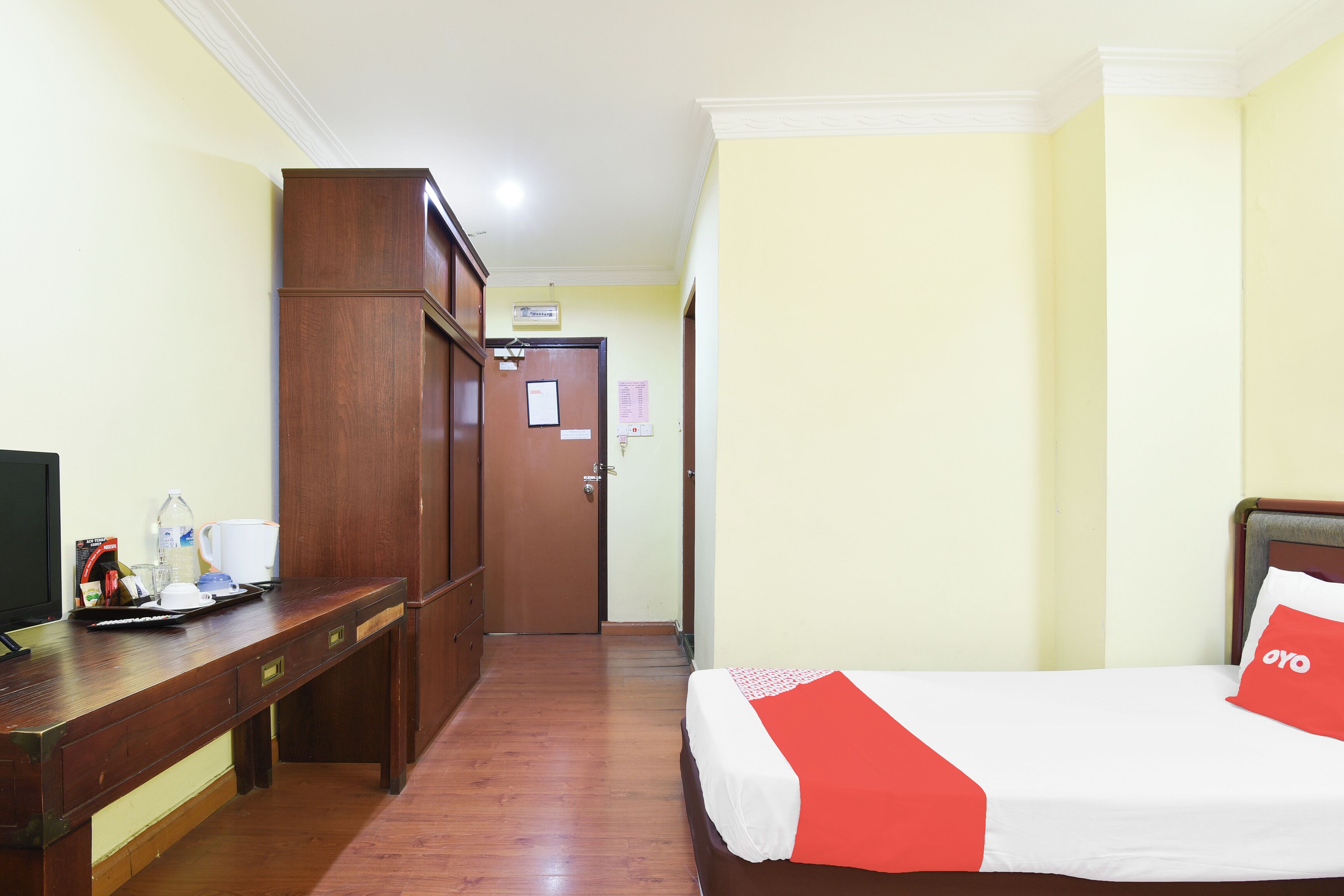 A hotel room with a bed, a desk, and a wardrobe.