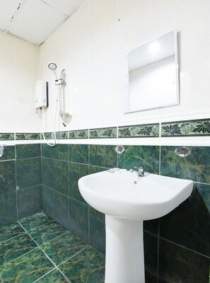A bathroom with a white sink, green and white patterned tiles, and a mirror above the sink. - Hotel O Kota Bharu Near War Museum Formerly Azam Hotel (Kota Bharu)