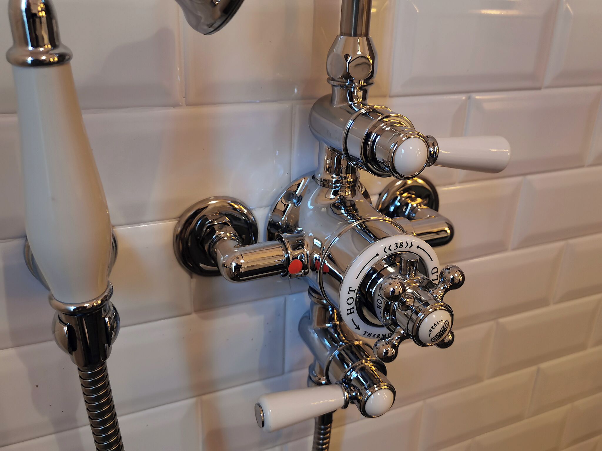 A bathroom with a chrome faucet, a showerhead, and a hand shower attachment.