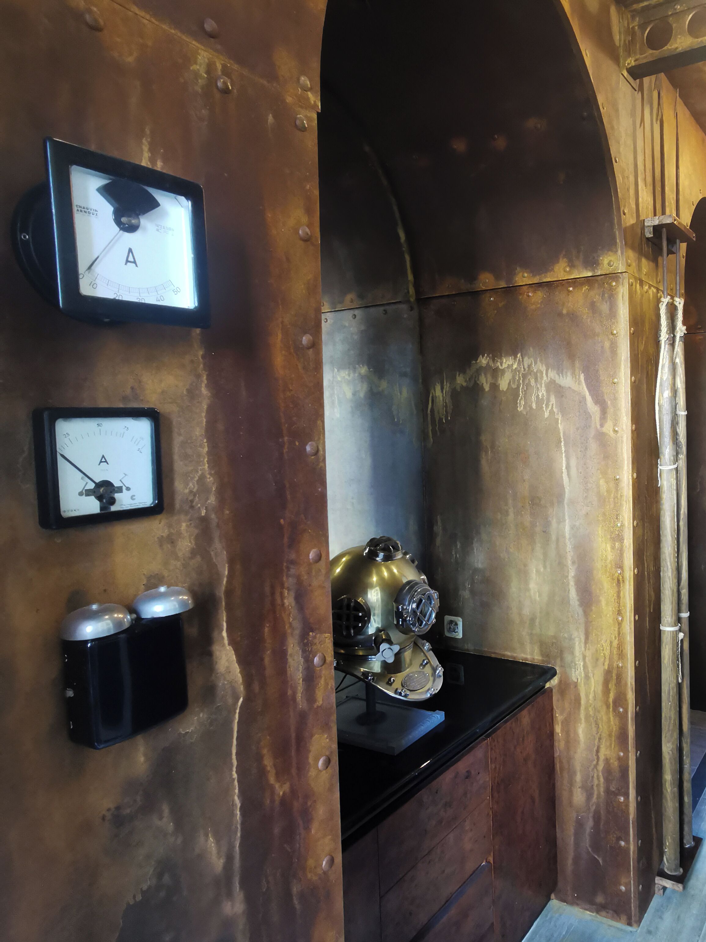 Una habitación de estilo vintage con diseño rústico e industrial, que presenta paredes de ladrillo visto, un extintor de incendios metálico y un reloj antiguo.
