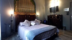 A bedroom with a large bed, a wall-mounted TV, and a unique vertical light fixture. - The Kraken Inn (Bergamo)
