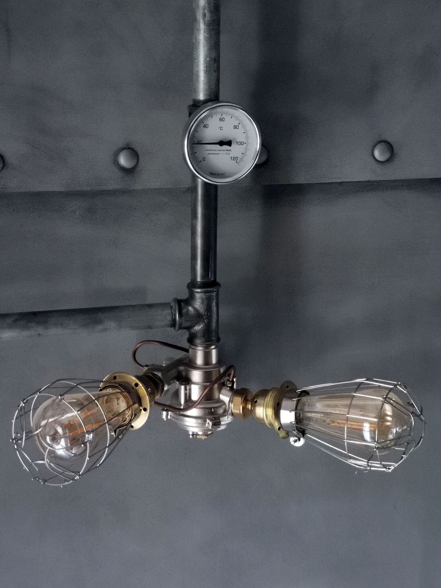 A vintage-style chandelier with exposed bulbs and a pressure gauge.