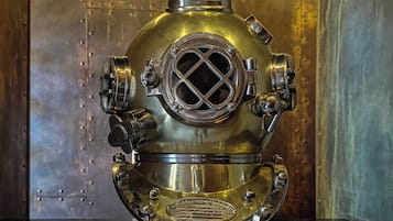 A vintage diving helmet with a circular window and ventilation holes, mounted on a stand.