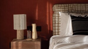 A bedroom with a bed, a nightstand, and a wall with a geometric pattern. - Mharo Khet (Jodhpur)
