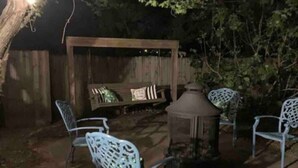 An outdoor patio area with metal chairs, a wooden bench, and a decorative lantern.